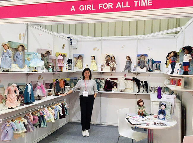 Meet the Dollmaker — Lee & Pearl interview Frances Cain, the creator of the A Girl for All Time® line of historical and modern 16 inch play dolls | Photo of Frances Cain and A Girl for All Time at Toy Fair, reproduced from the A Girl for All Time website, courtesy of Daughters of History Ltd.