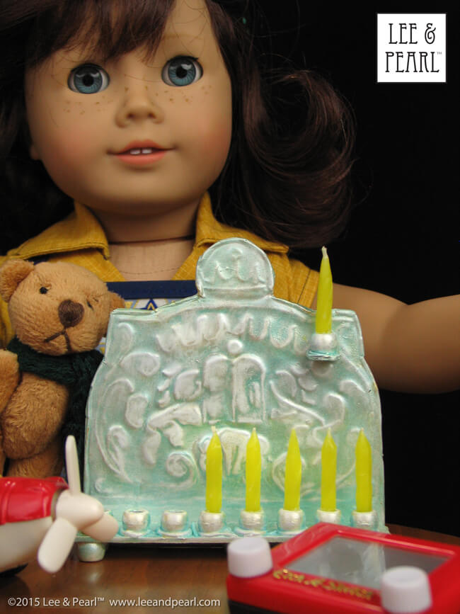 Happy Chanukah from Lee & Pearl! Make your 18 inch dolls their very own pressed metal Chanukah Menorah (Chanukiya) using a dollar store cookie sheet, cardboard, glue, plastic beads, a knitting needle, metallic paints and the techniques in our easy VIDEO TUTORIAL.